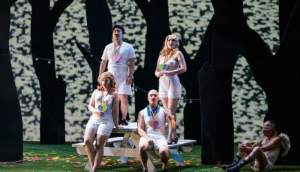 (L-R) Fiordiligi (soprano Sarah Tucker), Ferrando (tenor Konu Kim) Guglielmo (baritone John Brancy), and Dorabella (mezz-soprano Samantha Hankey) with Cupid (Jack Missett) r in San Diego Opera's COSI FAN TUTTE (February, 2022). Photo by Karli Cadel.